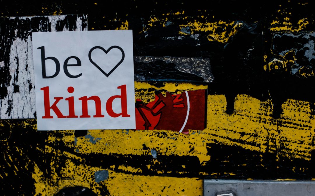 A graffiti'd wall with "Be Kind" painted on it.